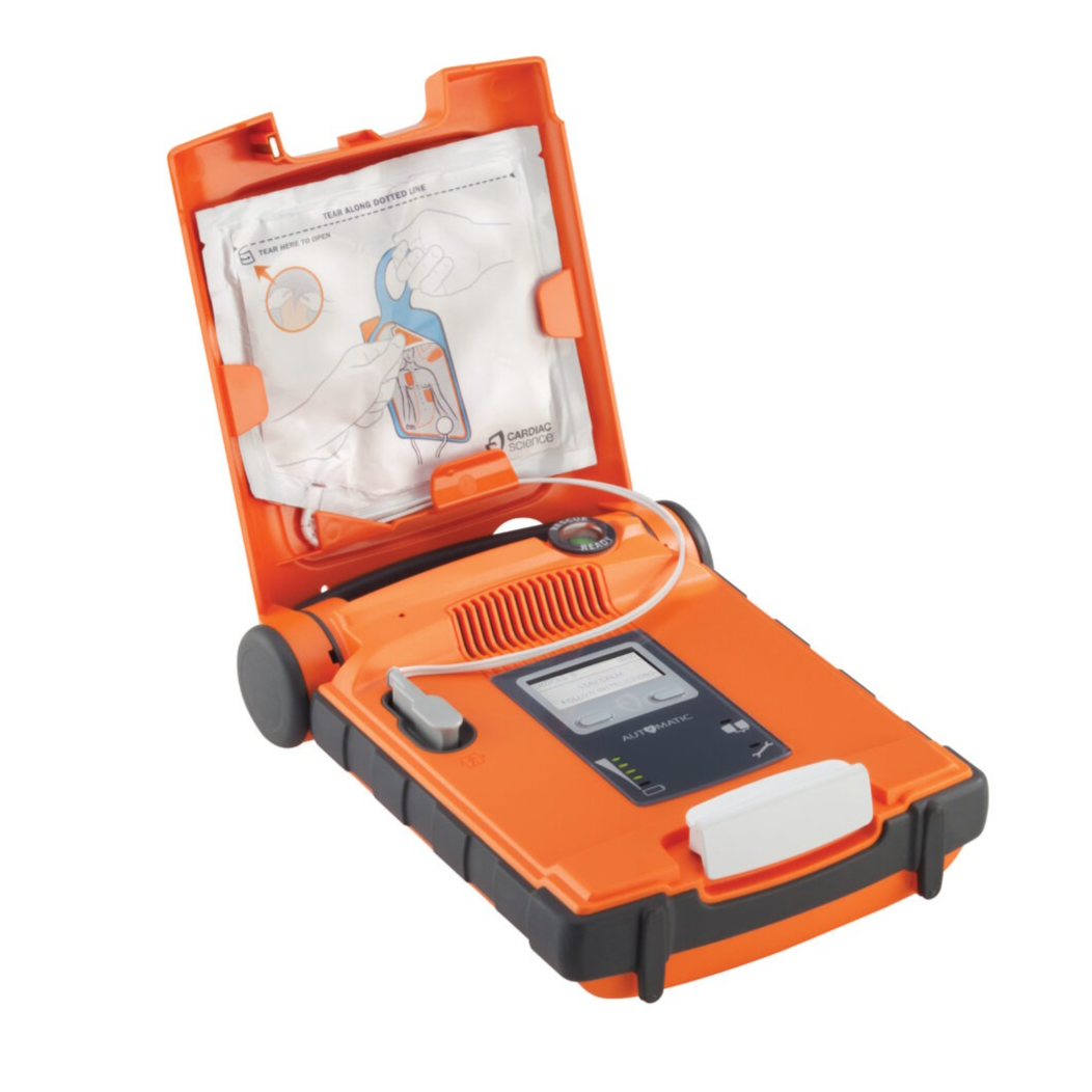 An open orange and black Cardiac Science G5 BILINGUAL AED, featuring semi-automatic shock delivery with Rescue Ready technology, has an instruction sheet visible inside the lid.