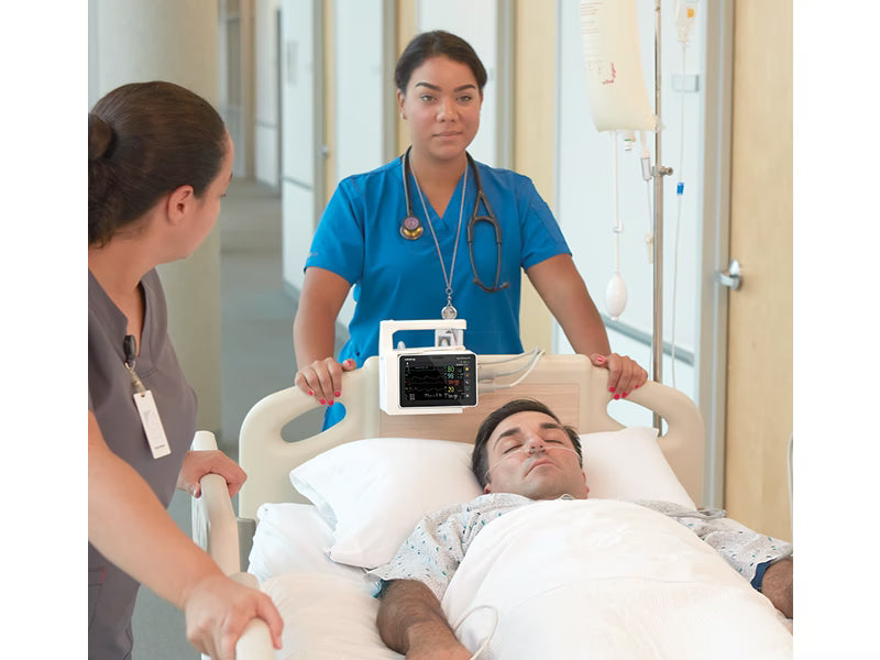 Two healthcare workers push a hospital bed with a patient using a Mindray BeneVision N1 portable patient monitor.