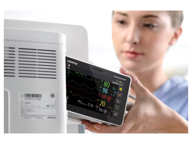A medical professional inserting a Mindray BeneVision N1 patient monitor into a bedside dock.