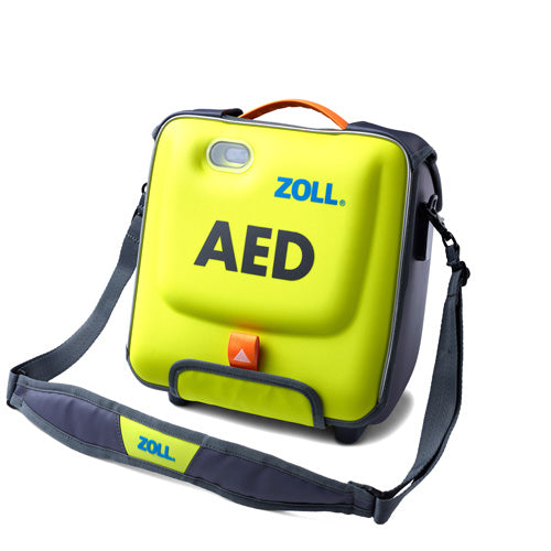 A yellow and black ZOLL AED (Automated External Defibrillator) device fits snugly in the ZOLL AED 3 Carry Case by ZOLL, which features a shoulder strap for easy portability. The case, labeled "AED" in large black letters, has a handle at the top and an orange latch for secure closure.