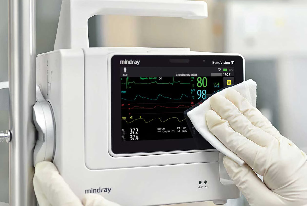 A gloved hand cleaning the touchscreen of a Mindray BeneVision N1 patient monitor.