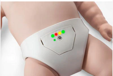 A baby is wearing a high-tech, latex-free diaper with colored indicator lights and a small circular button on the front, similar to modern features found in Prestan's Professional Series INFANT Training Manikins.